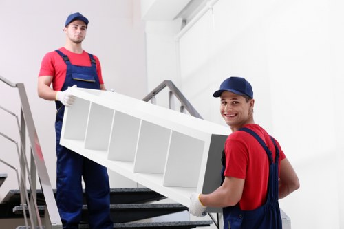 Two movers carrying a sofa from a flat in Fortis Green